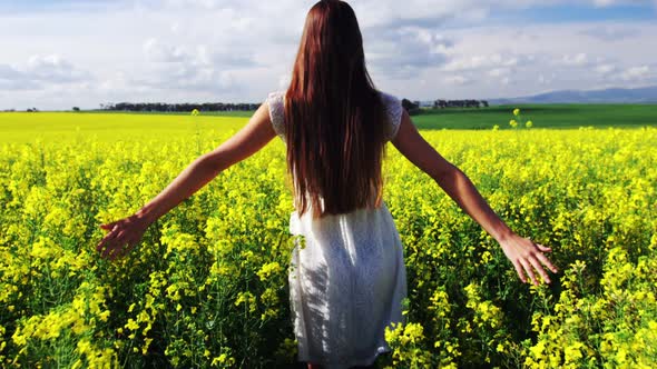 Woman touching flowers while walking in field