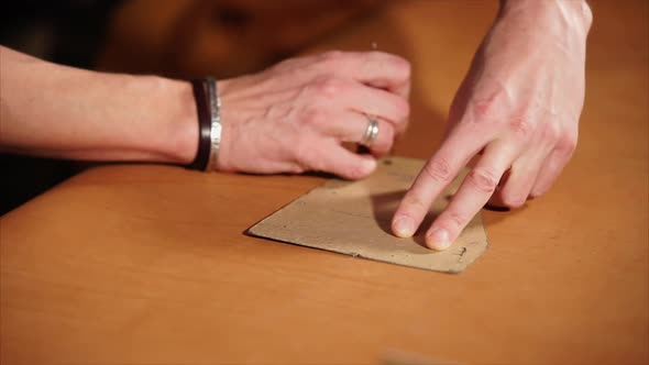 Tailor Draws Lines on the Piece of Leather