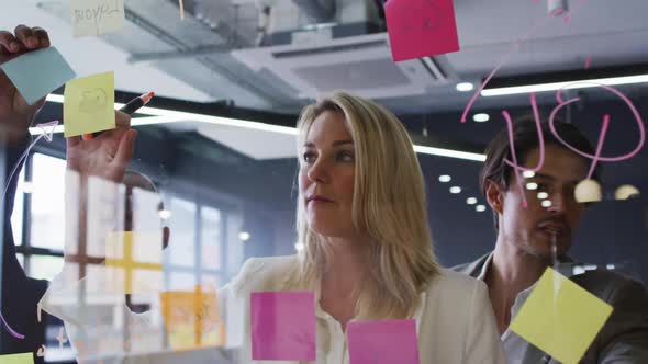 Diverse business people standing using a board brainstorming in modern office