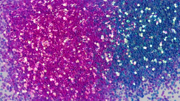 Blowing Out Pink and Blue Glitter on White Background Gloss Powder Closeup
