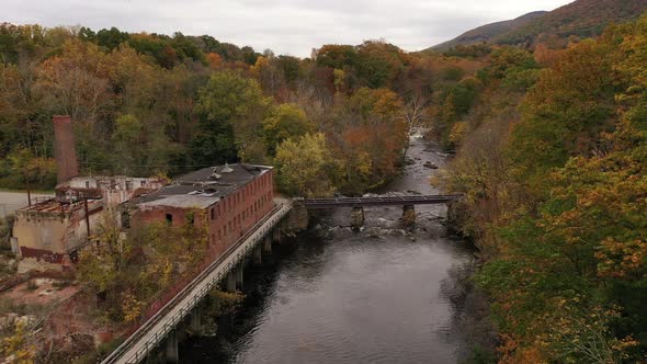 An aerial shot of the colorful fall foliage in upstate NY. The camera dolly in over a black river wi