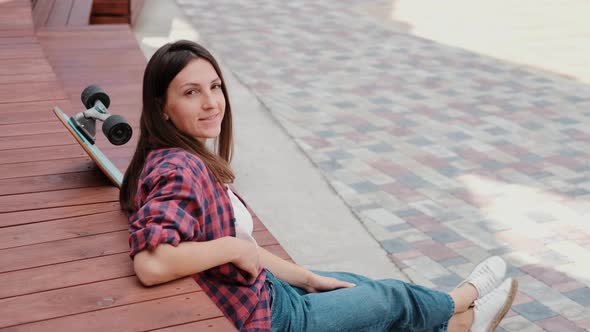 Girl Student Skateboarder is Engaged in Lessons on Her Laptop Remotely in the Fresh Air