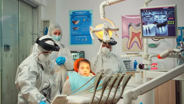 Dentistry Doctor in Protective Suit Using Sterilized Dental Tools Examining Kid Patient
