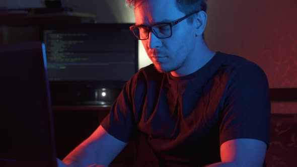 Looking Into the Camera a Man in a Dark Room at the Computer in Glasses