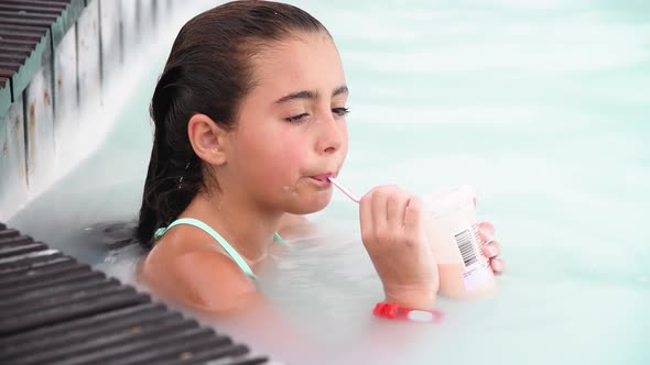 Young Girl Relaxing Sipping Fruit Juice in a Natural Pool Slow Motion