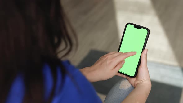 Closeup of Woman Holds Mobile Phone Smartphone and Swipes Photos or Pictures Left Indoors of Home