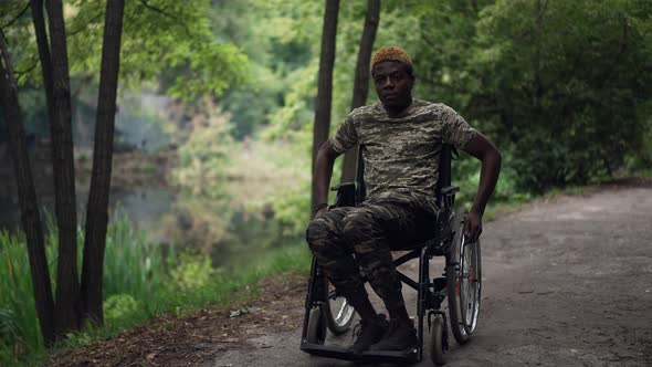 Wide Shot Sad Young Soldier in Wheelchair Riding in Summer Forest Looking Away