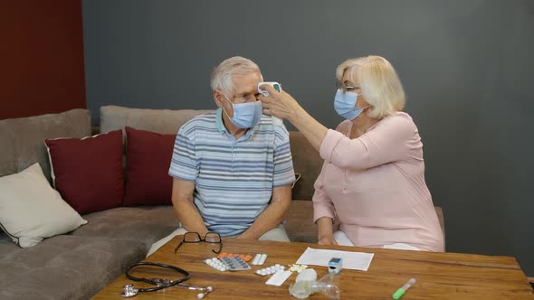 Senior Couple Measures Temperature with Contactless Digital Thermometer During Coronavirus Lockdown