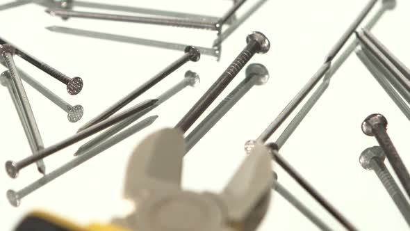 Mini Cutters with Yellow, Gray Handle on White Among a Lot of Nails, Rotation, Reflection, Close Up