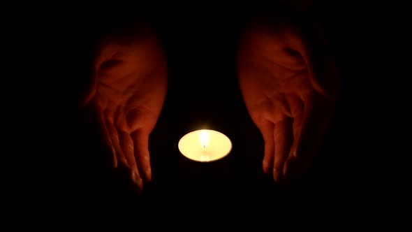 Hands Holding a Burning Candle in Dark 001