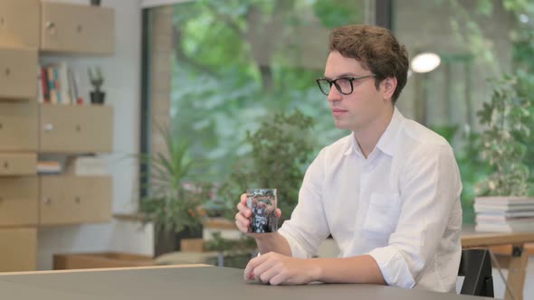 Young Man Drinking Water While Sitting in Office