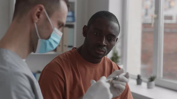 Man Watching Doctor Preparing for Injection
