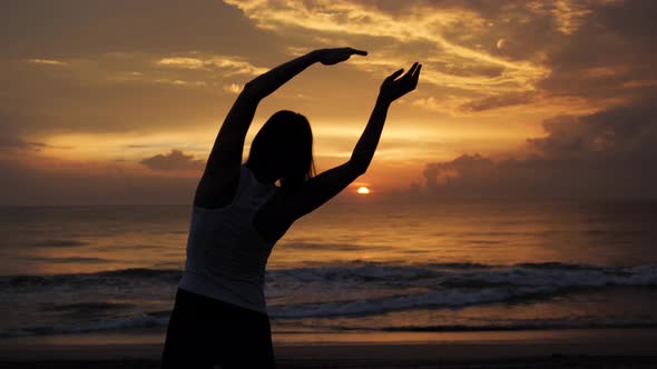 Young Healthy Woman Practicing Yoga on the Beach at Sunset Ocean Waves