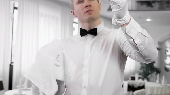 A Male Waiter in White Gloves Wipes a Wine Glass
