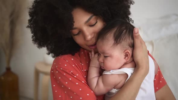 Young Mother Holding Daughter in Hands and Hugging Sitting on Bed in Home Bedroom Spbd