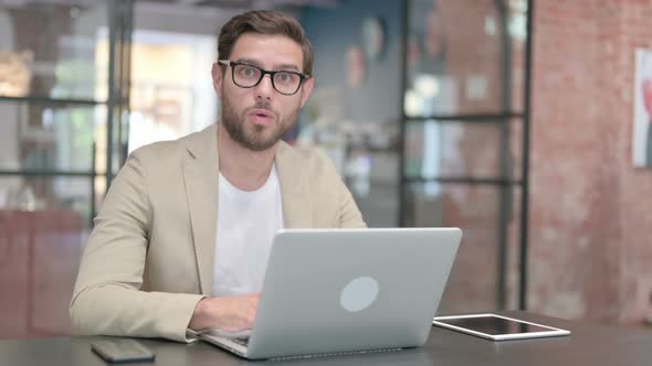 Young Man with Laptop Feeling Shocked