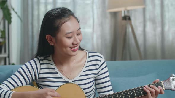 Close Up Of Asian Woman Enjoy Playing A Guitar At Home