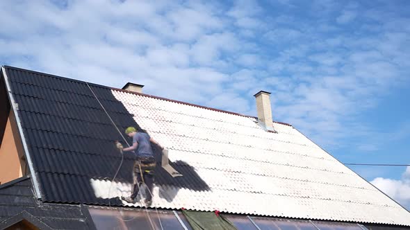 Worker sprays black paint on the roof