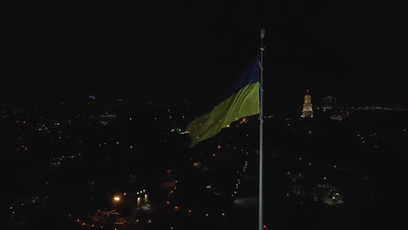 Aerial View of a Flag of Ukraine Flailing in the Wind at Night in Kyiv