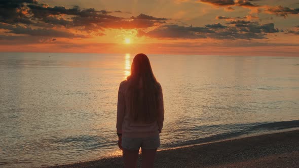 Admiring Sunrise on Seashore Woman Raising Up Her Hands