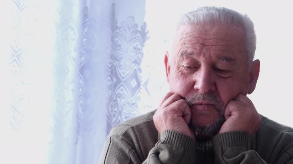 An elderly gray-haired man has a headache.