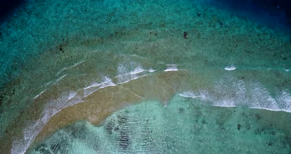 Wide angle above clean view of a white sandy paradise beach and blue sea background in colorful 