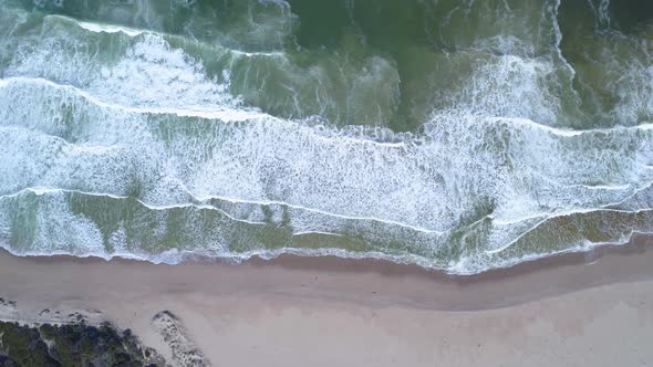 Aerial top down shot showing breaking waves on pristine, unspoiled beach in Kleinmond, South Africa