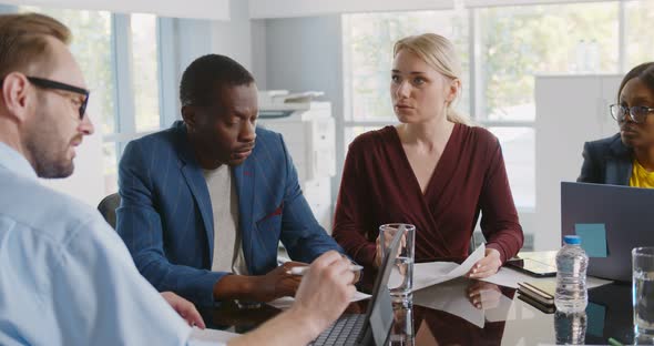 Serious African Executive Listening to Employees Report Looking at Tablet Screen