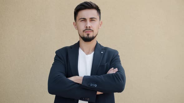 Portrait of Selfassured Young Man Standing Outdoors with Arms Crossed and Looking at Camera with