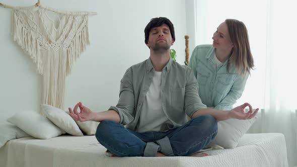 Man Meditating Sitting on Sofa While Active Energetic Woman Jumping Playing