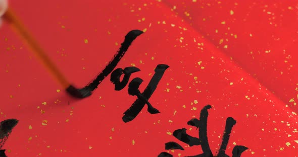 Writing Chinese calligraphy on red paper for new year