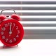Red alarm clock ringing at twelve clock on background of blinds. - VideoHive Item for Sale