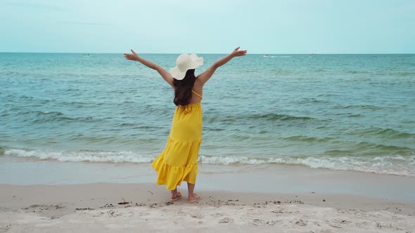 freedom woman with arms raised on the sea beach with wind blow