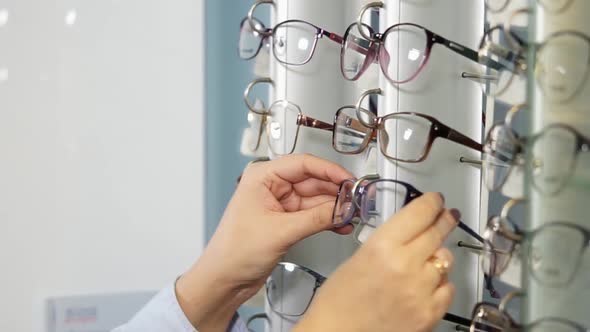 Close Up Shot of Female Hands Lady Takes Out Glasses From Stand