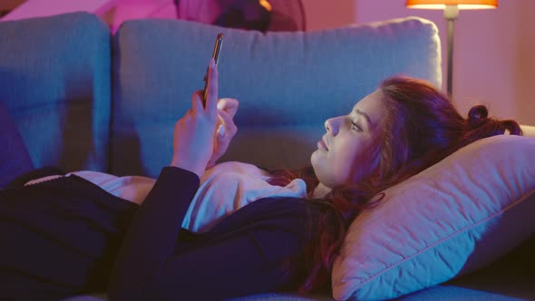 Young Woman Using Smartphone While Laying On Couch.