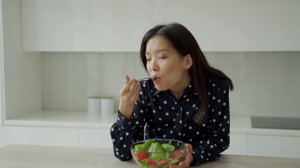 Attractive Asian Woman Eats a Salad of Fresh Vegetables
