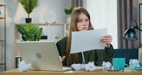 Girl in Casual Clothes Working on Laptop with Paper Report and Tearing it Unsatisfied of Results