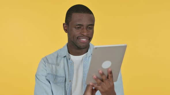 Young African Man Using Digital Tablet, Yellow Background 