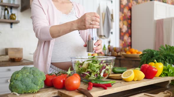 Healthy Pregnancy Concept. Pregnant Female Cooking Salad, Adding Salt And Pepper.