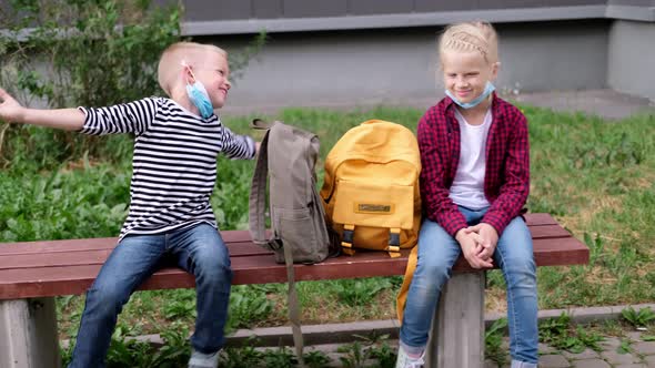 Back to School Girl and Boy Children Sit Talking on Bench Near the School Keeping Social Distance