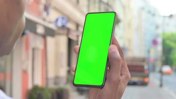 Rear View of African Man Looking at Smartphone with Green Chroma Screen