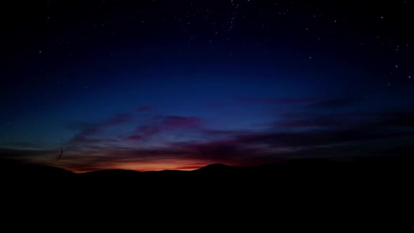 Timelapse red sunset over hills with starry sky