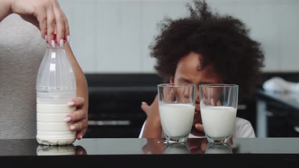 White Mother and Her Mixed Black Daughter at the Kitchen  Woman Pouring Milk in the Glasses