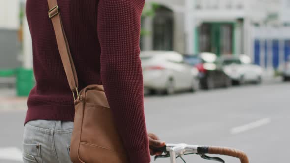 African American Man walking in the street with his bike