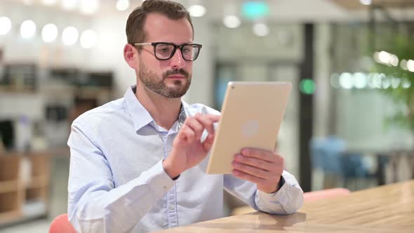 Serious Businessman Using Tablet in Office