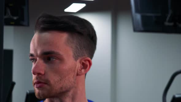 A Young Fit Man Jogs on a Treadmill in a Gym - Face Closeup