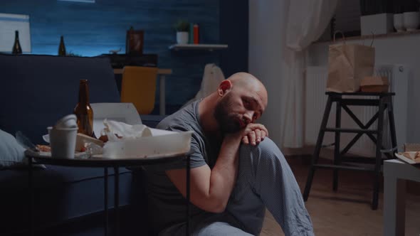 Depressed Man Sitting on Floor Looking at Camera with Dissapointed Expression