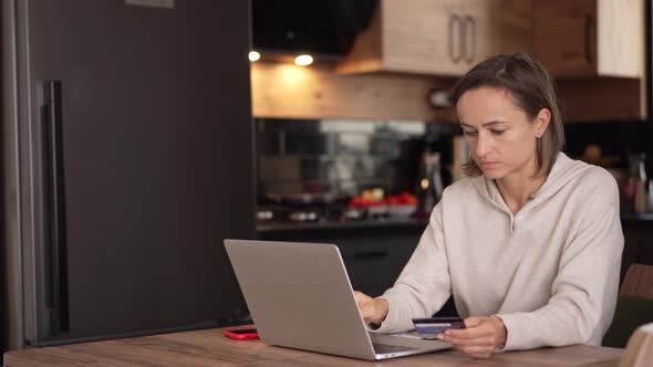 Caucasian Woman Makes an Online Payment Using a Bank Card and Laptop