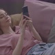 Girl Listens To Music With Headphones While Lying On The Couch And Looks Into A Smartphone - VideoHive Item for Sale