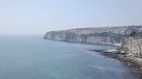 Dolly left to right over Jurassic Coastline in Seaton, United Kingdom. Waves from the ocean crash ag